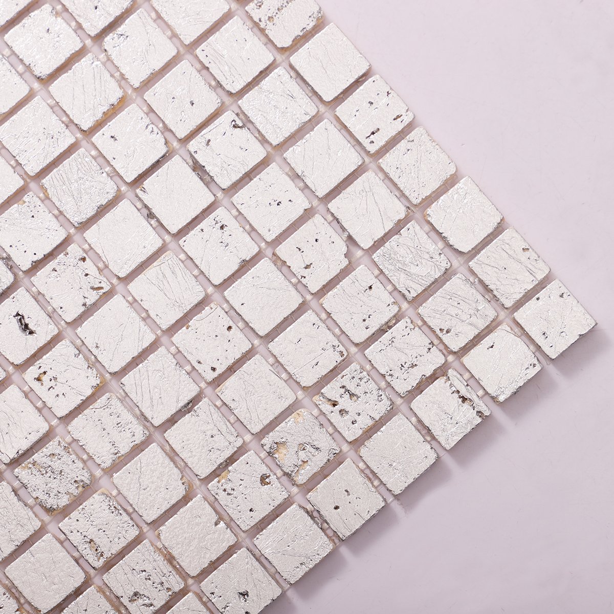 Detailed close-up of silver foil travertine mosaic wall tiles.