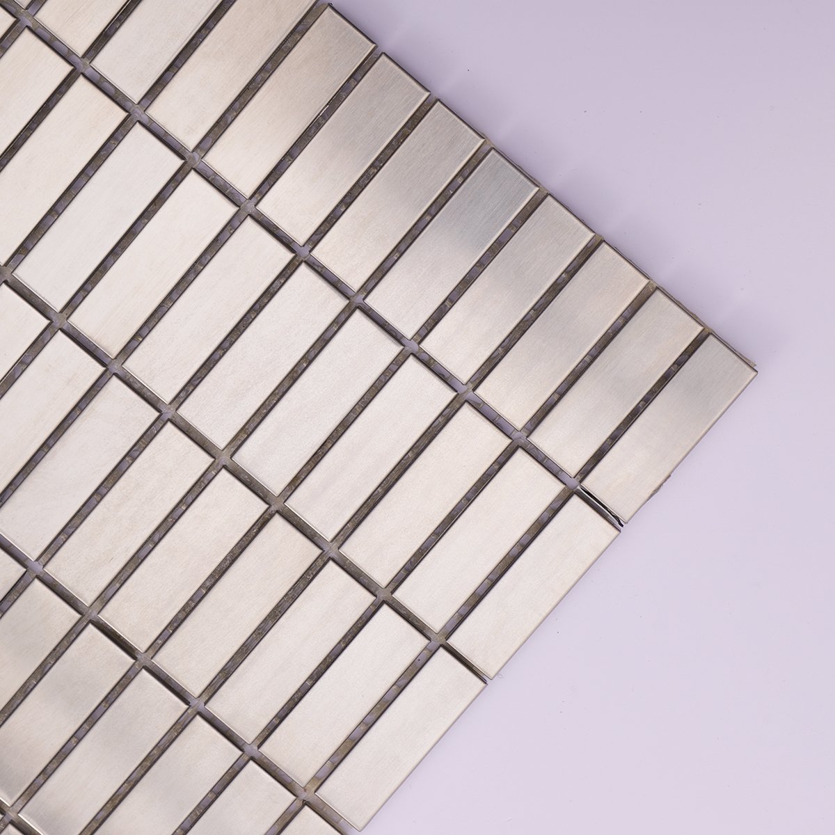 Close-up highlighting the linear brushed texture on stainless steel tiles