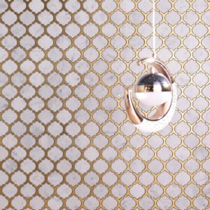 Living room wall with Carrara white marble and gold metal arabesque mosaic tiles.