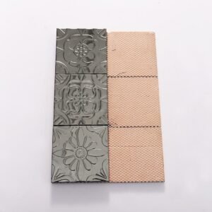 Svart metallmosaik i lapptäcksmönster med präglade blommotiv