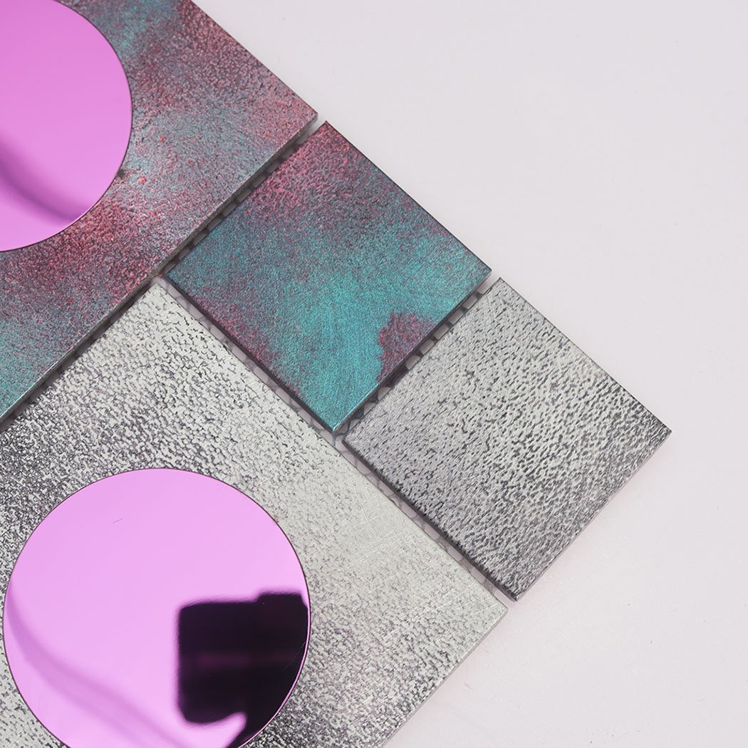 Corner detail of aluminum mosaic tile with teal blocks and pink round glass inserts