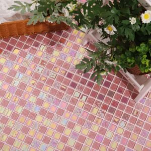 Pink iridescent mosaic tiles installed on a surface next to a white flower planter box.