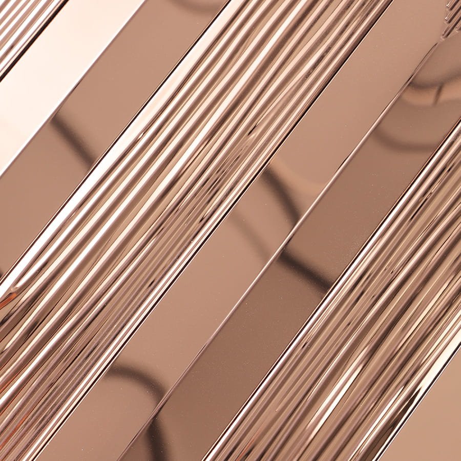 Detailed close up of rose gold metallic surface with alternating smooth and grooved stripes.