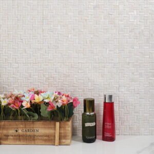 White mother of pearl basket weave wall with flowers and skincare bottles.