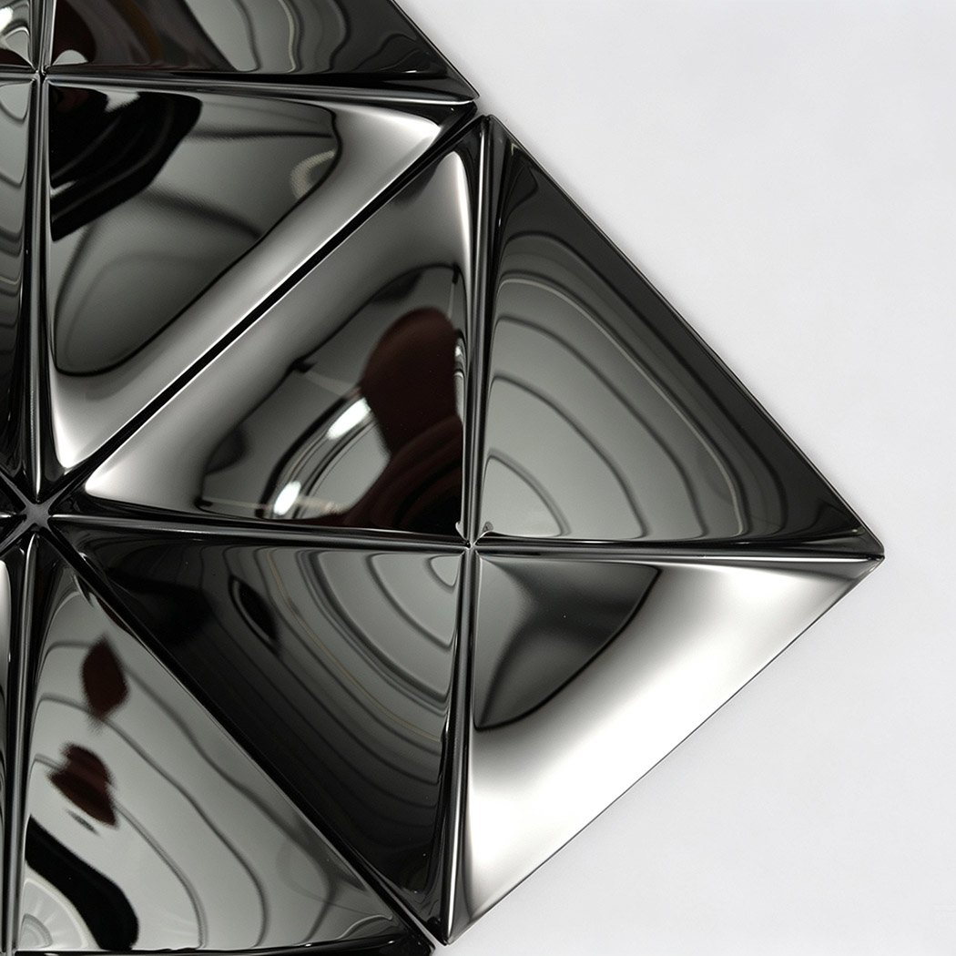 Close-up of black 3D shaped wall tiles with a reflective metal surface