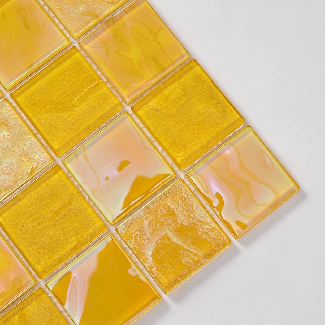 Corner close-up of bright yellow iridescent square glass mosaic tiles on white mesh