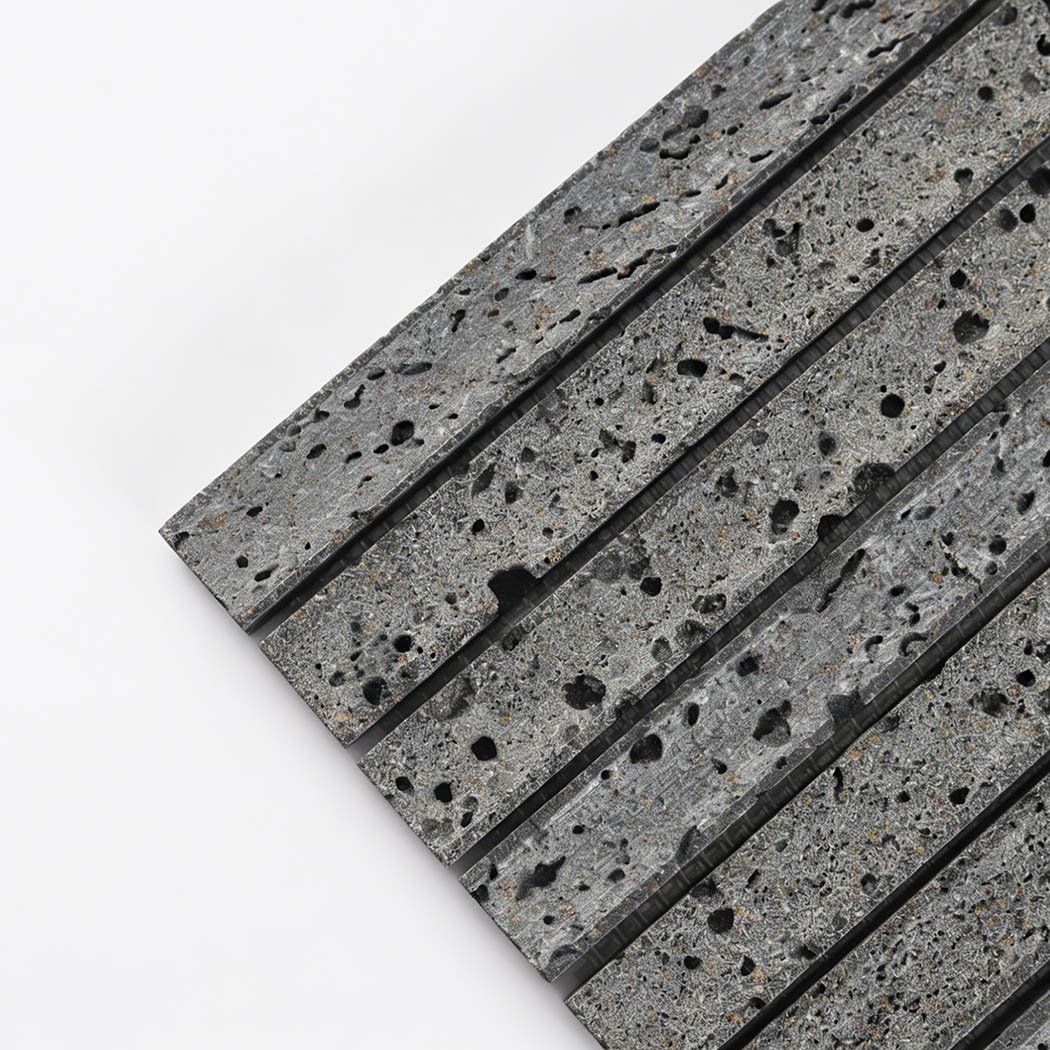 Close up corner view of gray lava stone linear mosaic tile with natural black pores