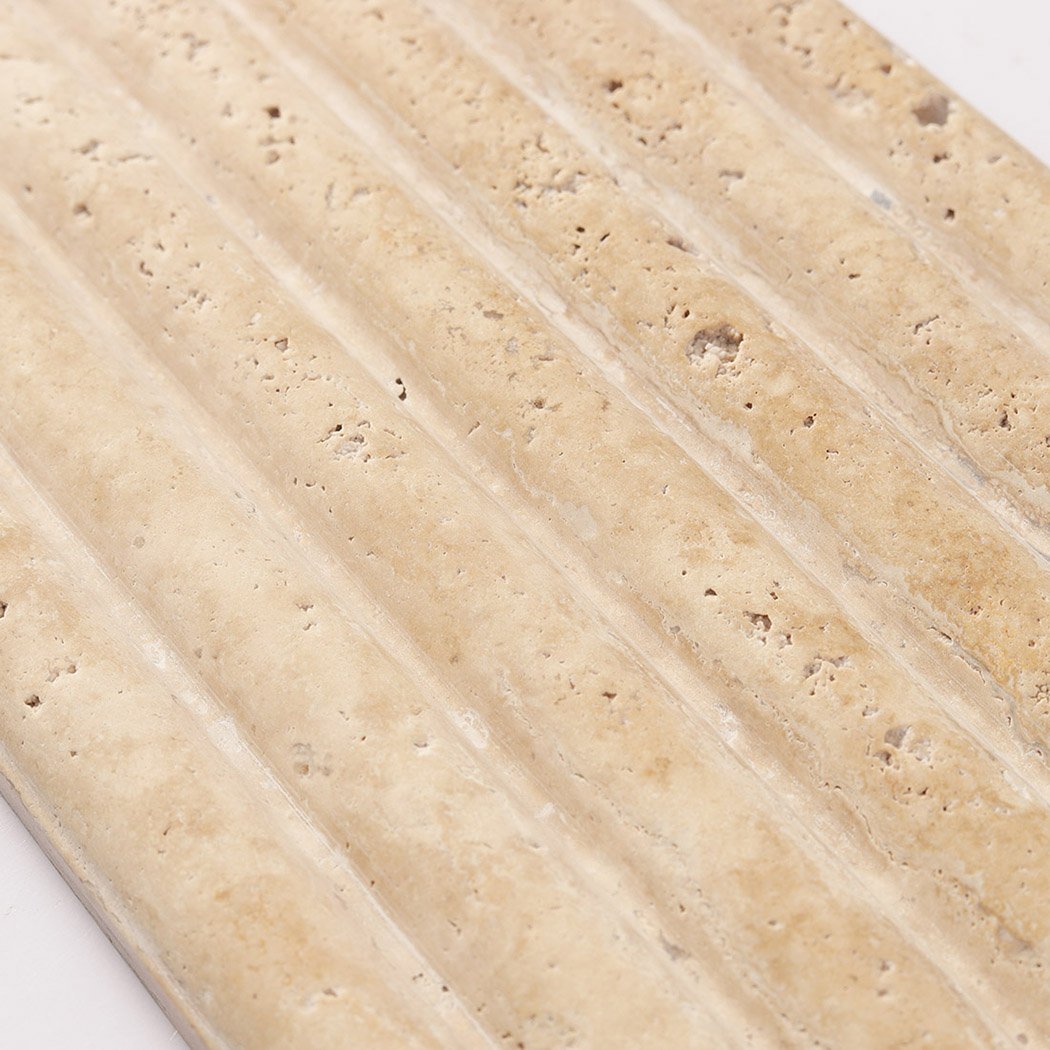 Macro view of ribbed beige travertine stone showing its natural porous surface.